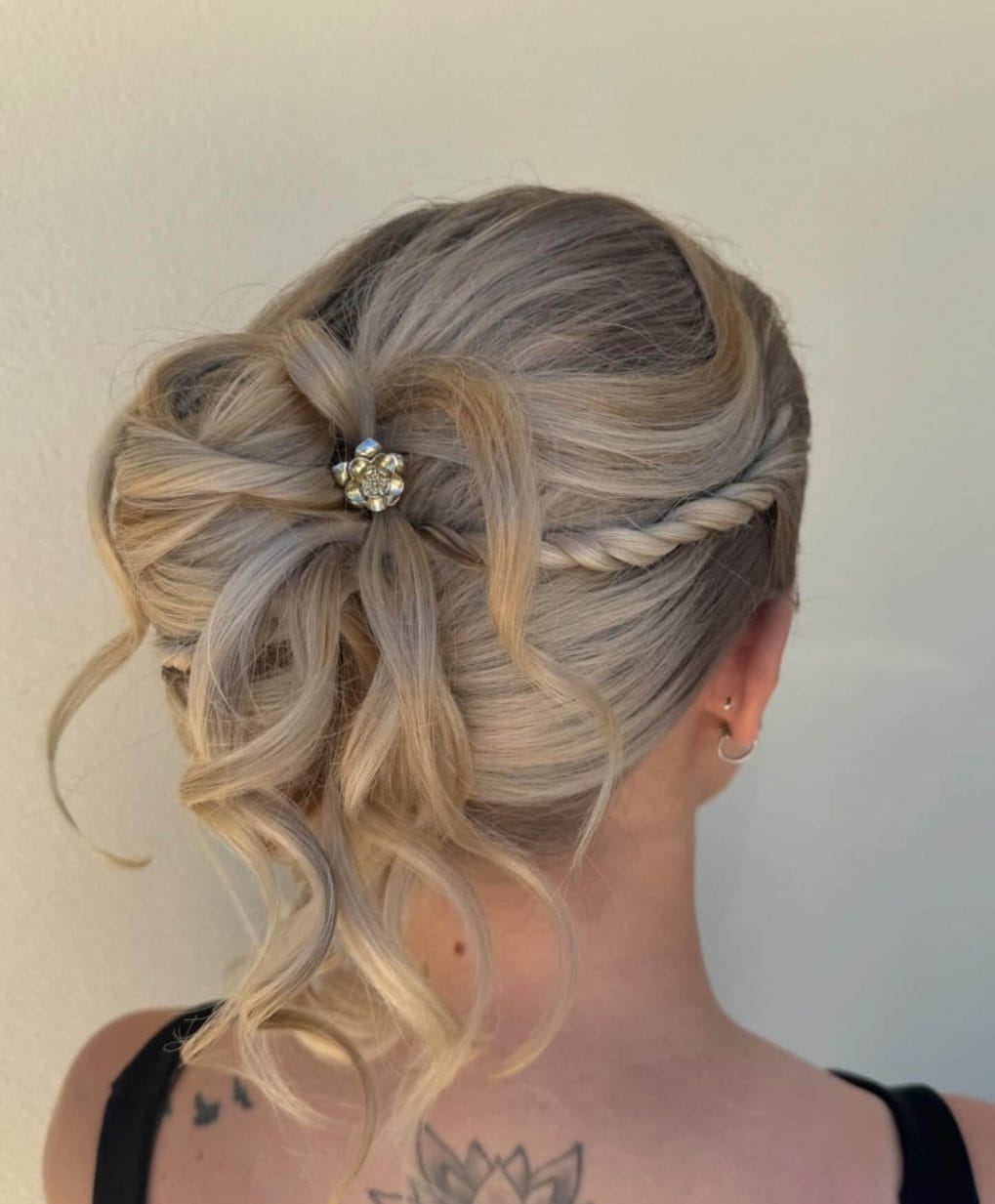 Curled updo with floral pin and blonde highlights.