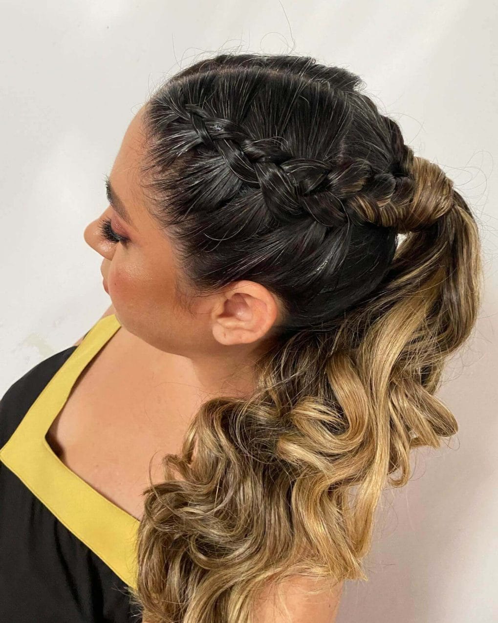 Braided crown circles the head above a sun-kissed curly ponytail