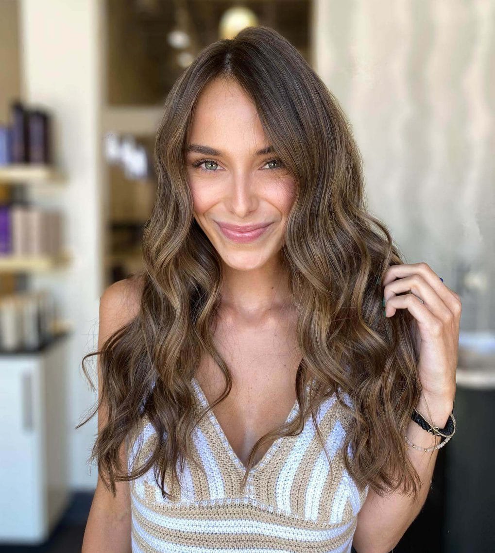 Sun-kissed long layers with caramel and honey highlights on hair.