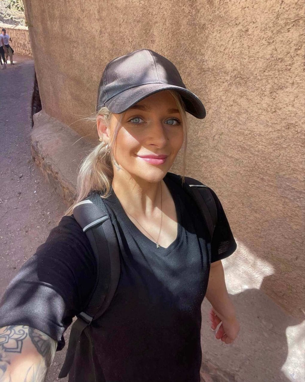 Light-haired hiker with ponytail under cap on sunny trail