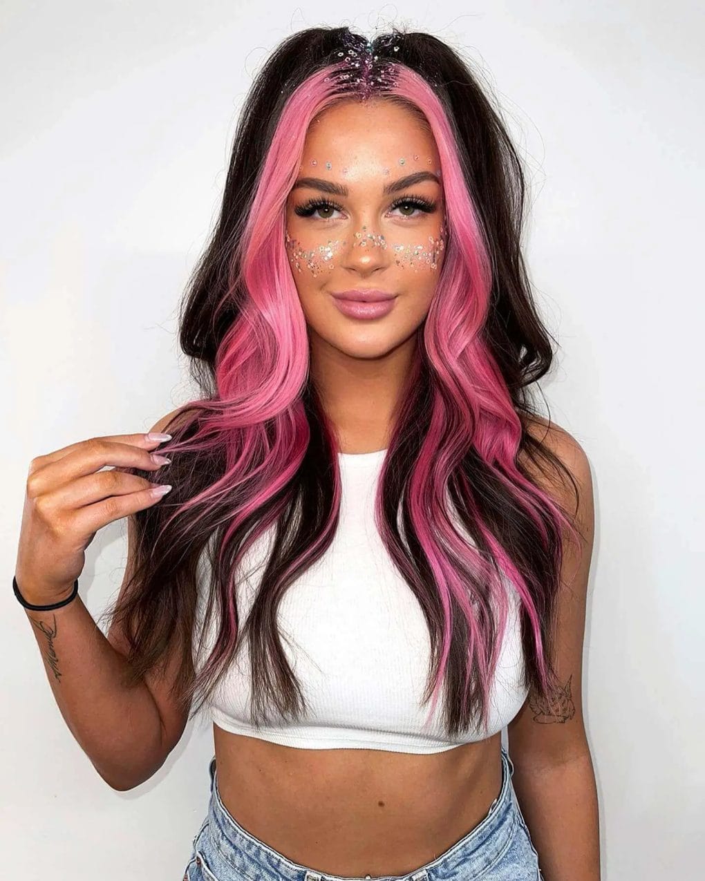 Bold pink balayage with soft waves and face gemstones, embodying festival sunset vibes.