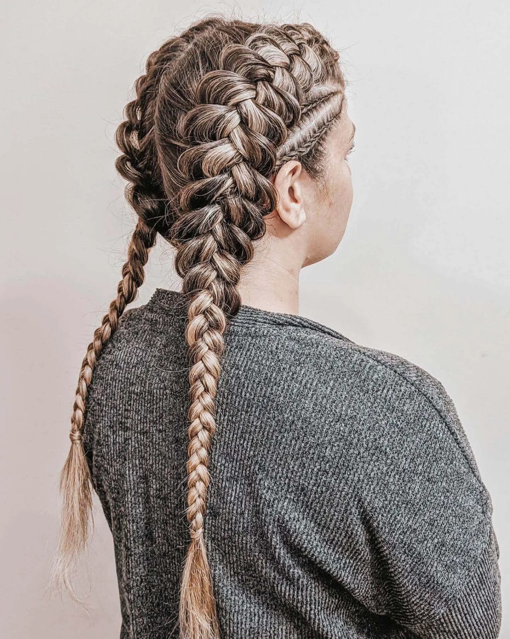 Symmetrical French braids merging into blonde-tipped ponytails.