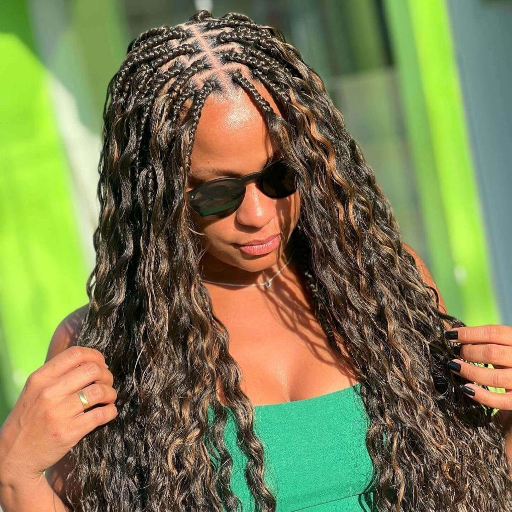 Tight braids at the top transition into loose, wavy strands with a warm glow