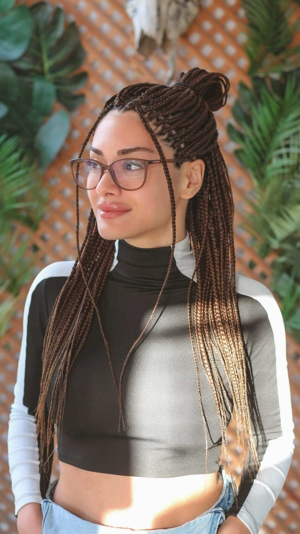 Playful top bun from numerous tight cinnamon brown plaits for softball