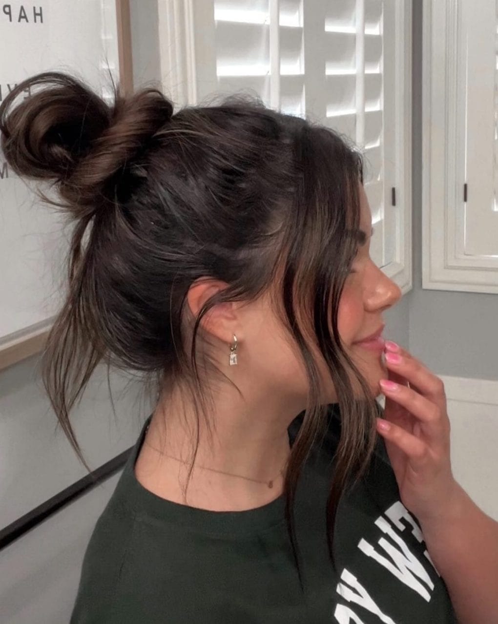 Casual top knot with loose strands in dark color for a laid-back softball style