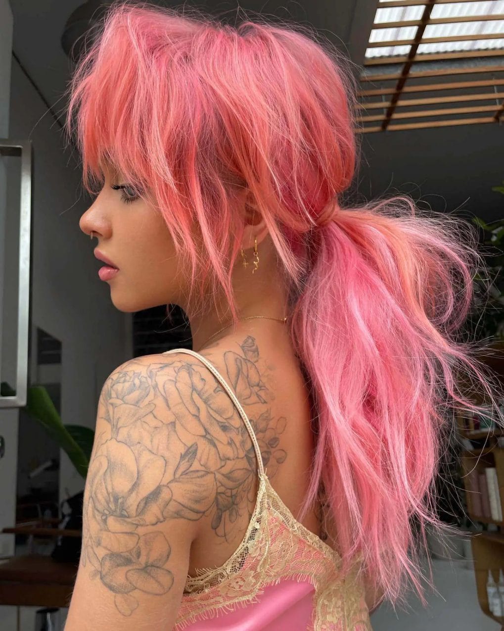 Tousled candy-pink ponytail with a cool, edgy vibe, complemented by rough choppy bangs.