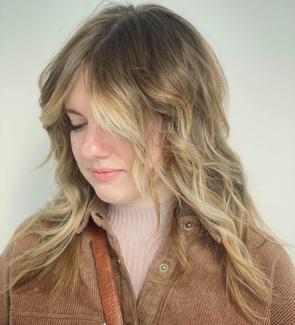 Tousled modern octopus hairstyle with brunette to honey blonde highlights.