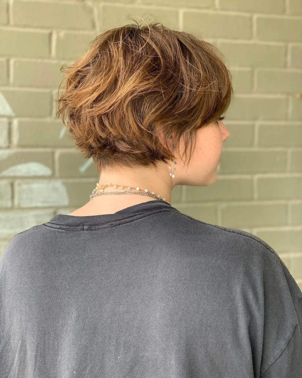 Layered bixie in light brown with a tousled look, shorter at the nape growing longer toward the face.