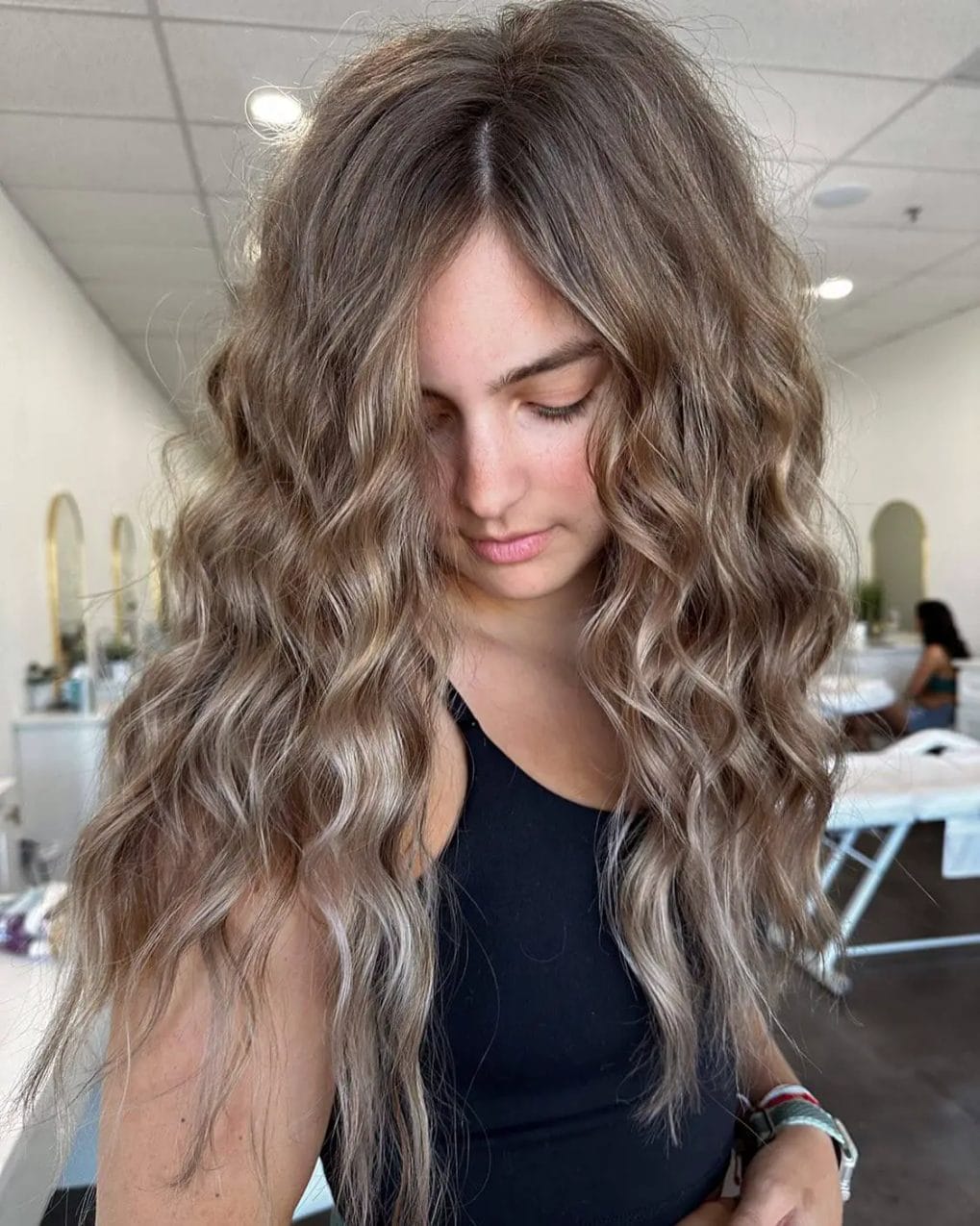 Tousled mane with beachy waves and sandy highlights on hair.