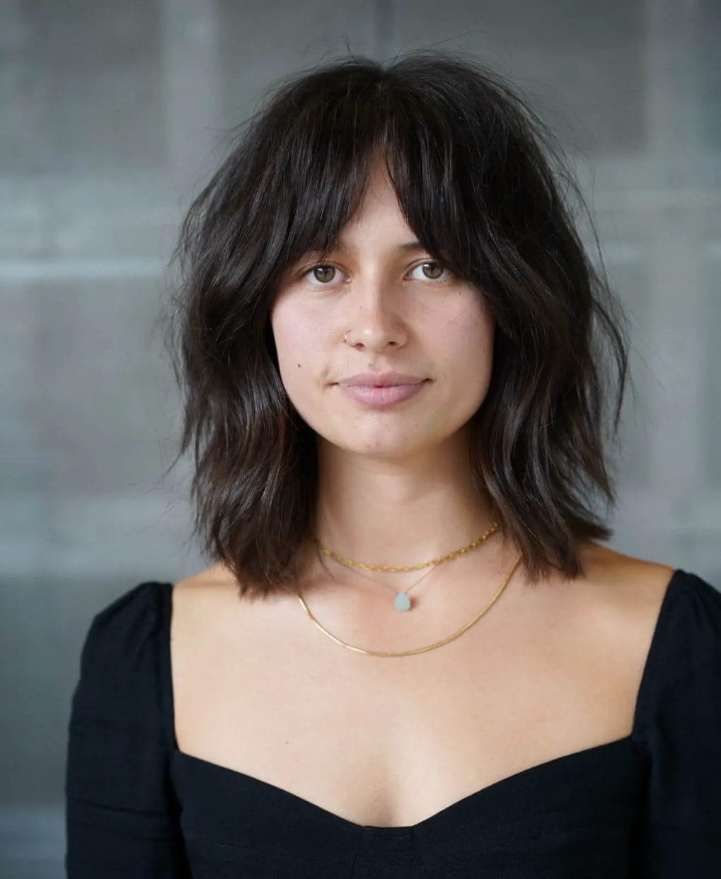 Tousled, shoulder-length lob with chocolate and caramel tones and chic curtain bangs.