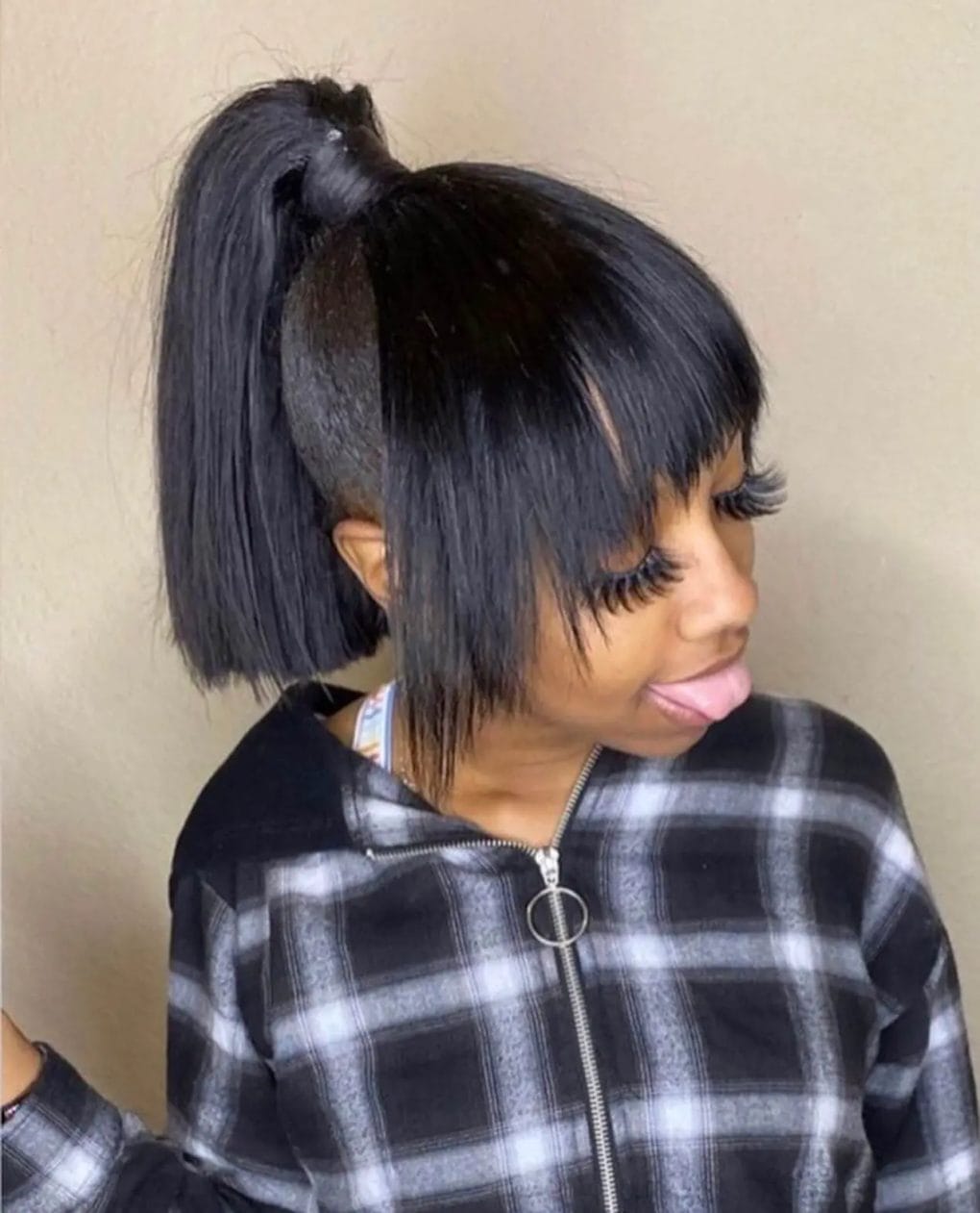 Trendy high ponytail with a textured bob cut in natural black, featuring straight-across bangs for a youthful edge.