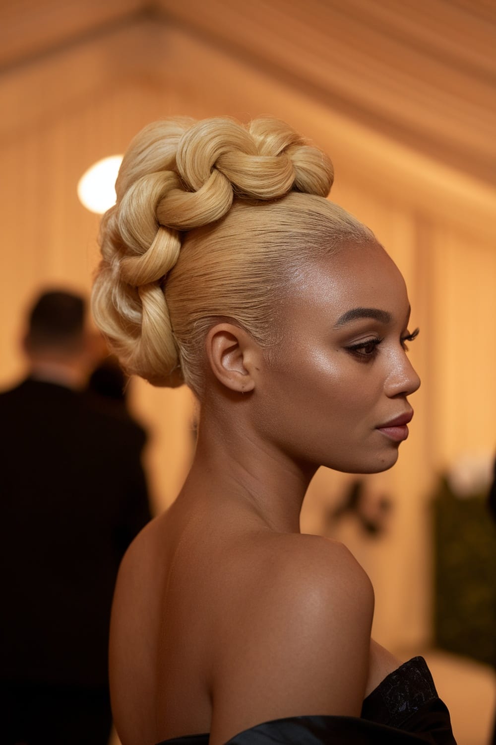 A woman showcasing a twisted honey blonde updo hairstyle with a sophisticated braided design.