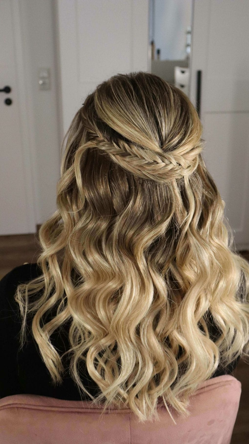 Tight twisty half-up braid crowns head leading into blonde curls