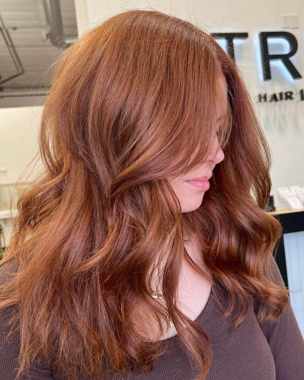 Uniform copper tone hair with long layers and side-swept style.