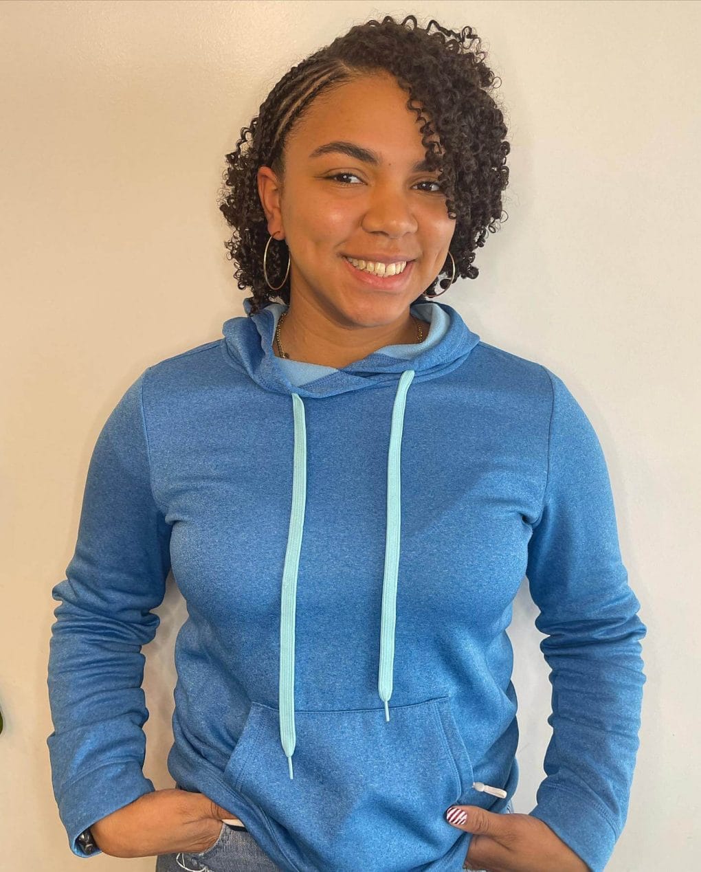 Haircut with tight curls on one side and neat cornrows on the other.