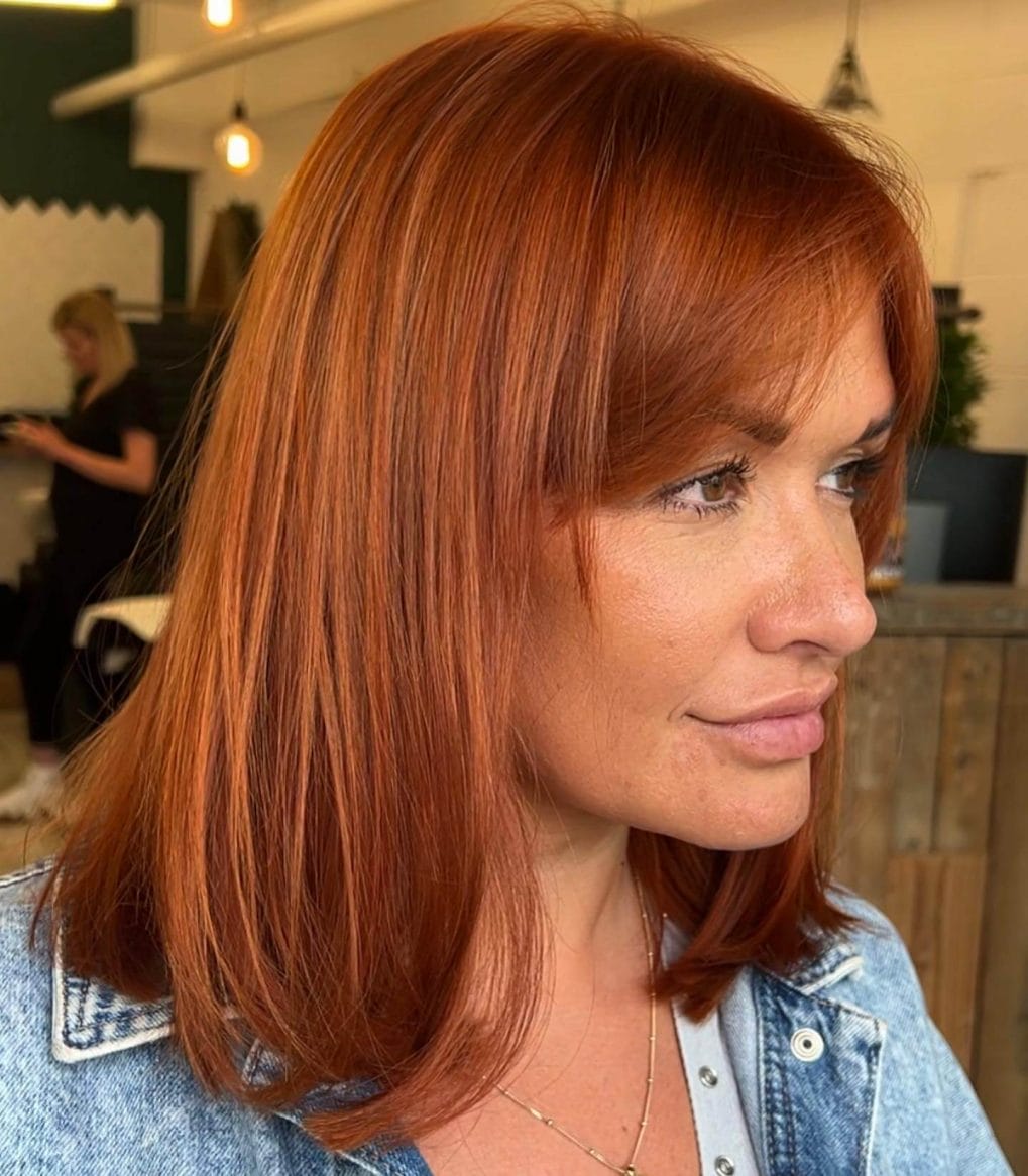 Vibrant copper sleek bob with straight-across bangs and subtle layers.