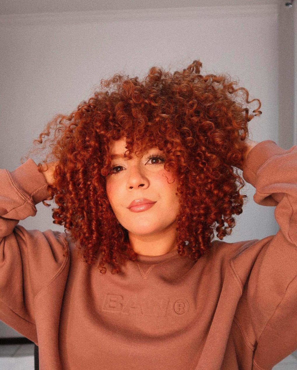 Vibrant copper-toned curly mane with expert layers.