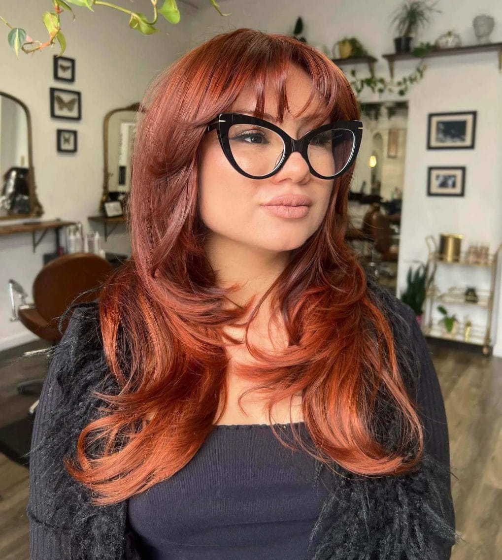 Sun-kissed copper waves with wispy fringe and bold glasses.