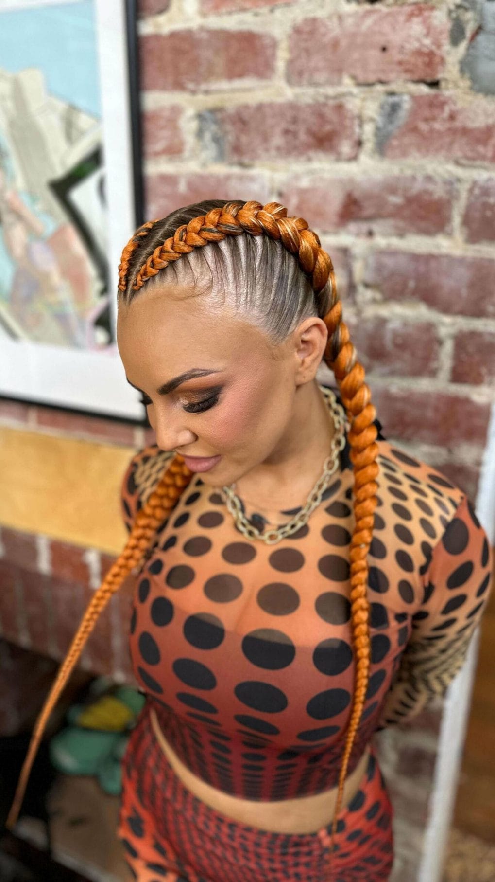 Fiery orange Dutch braids wrapping around a shaved head