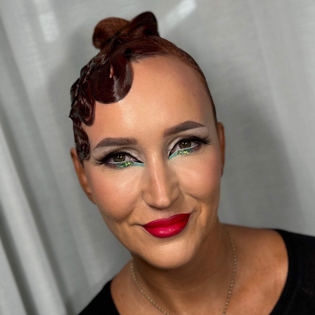 Sleek red updo with a singular playful curl