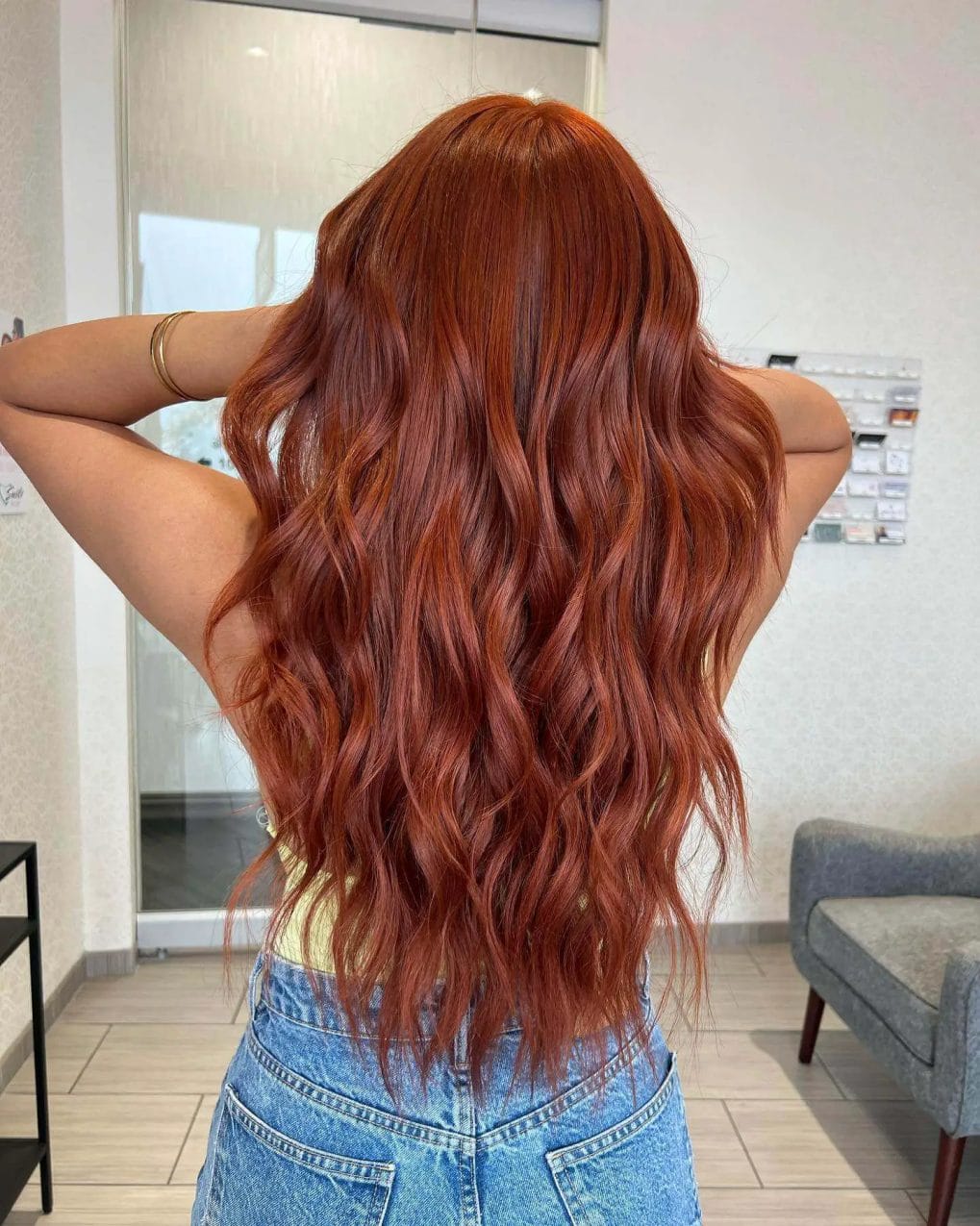 Vivid copper hair with highlights, long waves, and voluminous layers.