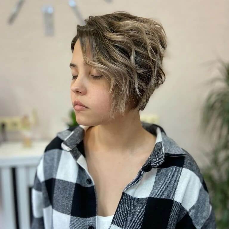 Voluminous blonde wavy pixie with a chic side fringe.