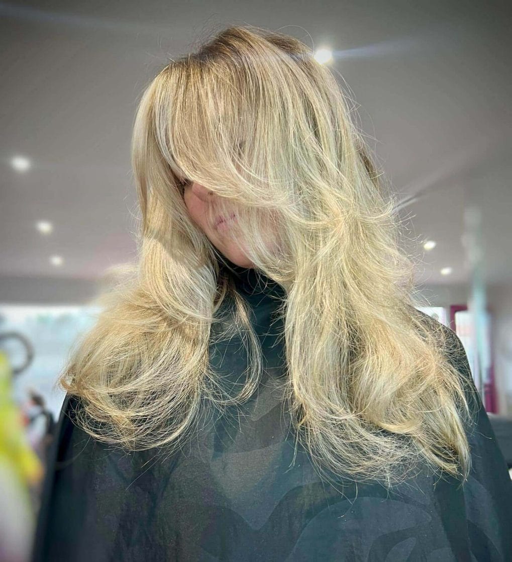 Voluminous blonde layers with 90s curtain bangs glam