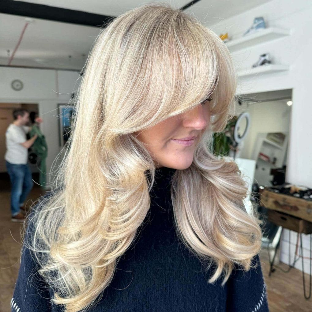 Voluminous blonde layers with curtain bangs 90s glam