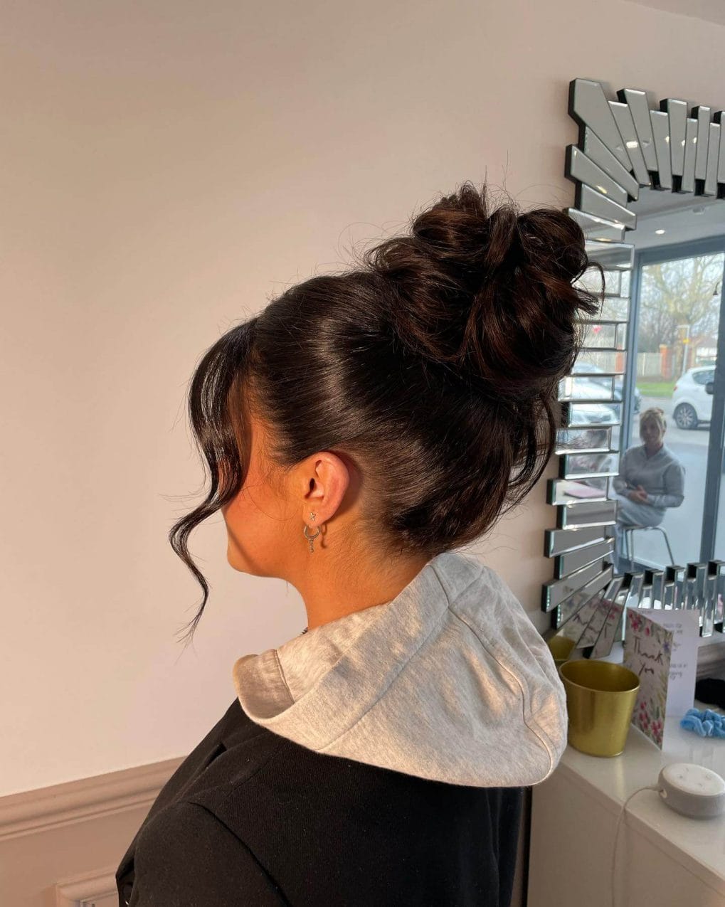 Voluminous dark tousled high bun with side-swept curl