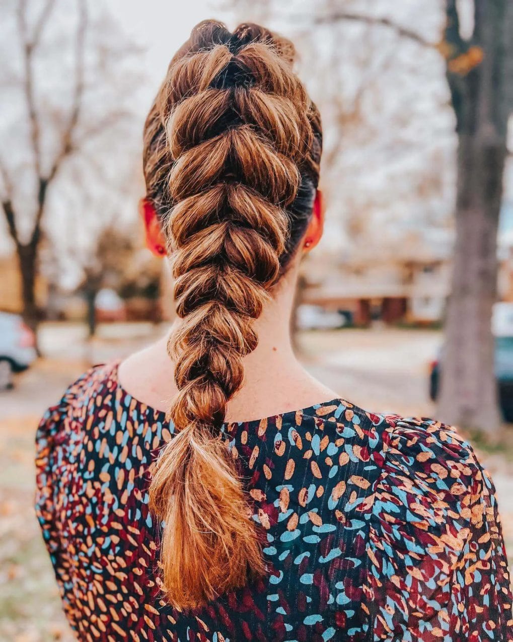 Voluminous French braid from crown into a full-bodied ponytail with chestnut and honey tones.