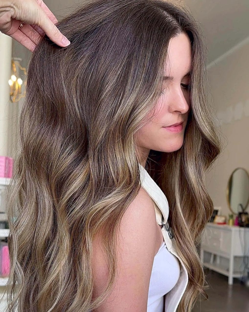 Voluminous layers with ash and golden highlights on hair.