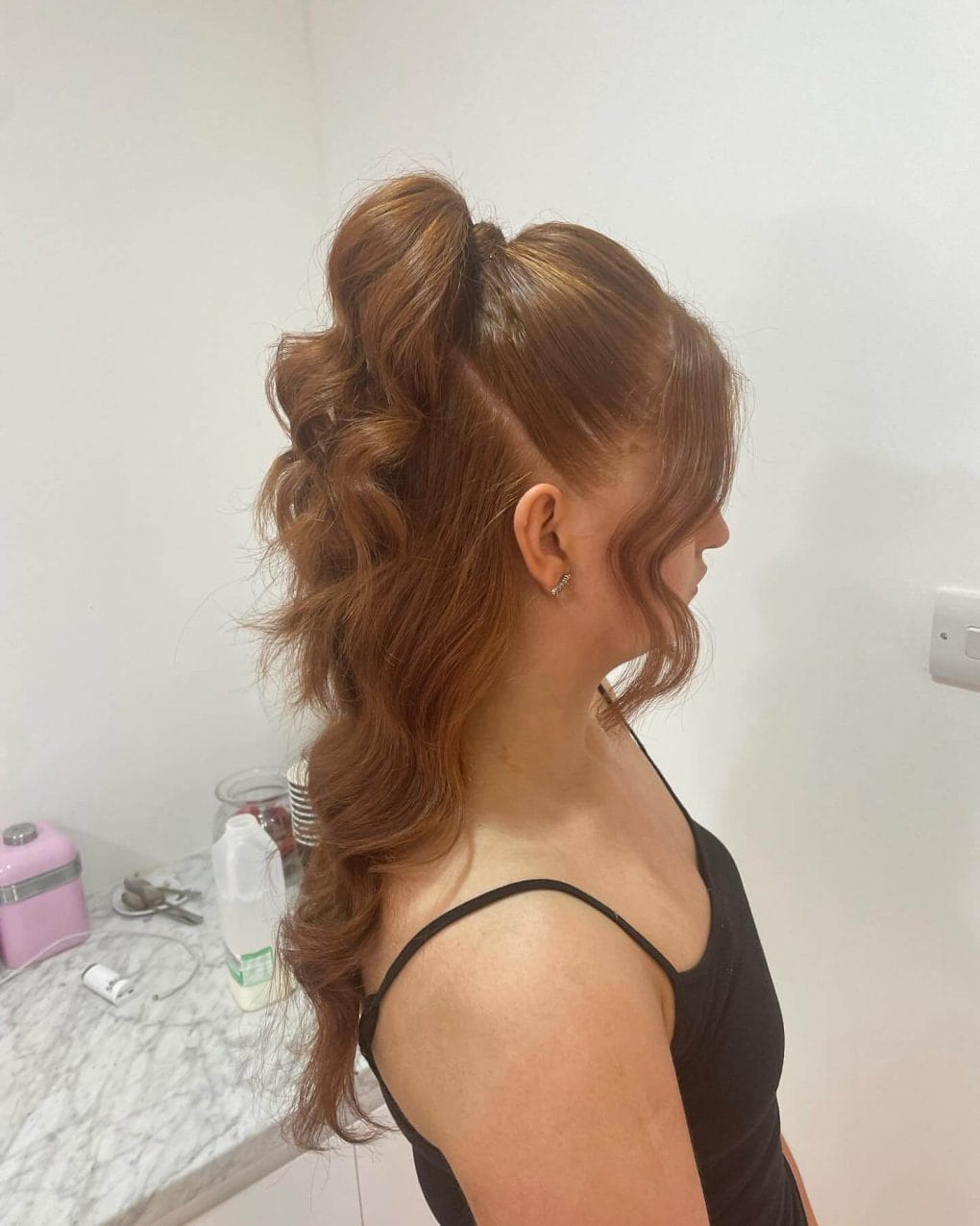 Half-up hairstyle with voluminous ponytail and soft reddish waves