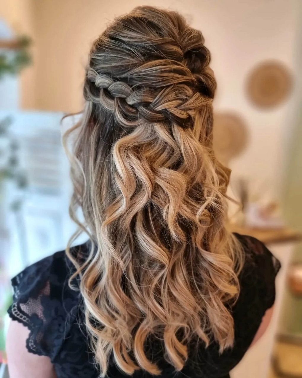 Half-up braid merges into warm, curling blonde locks