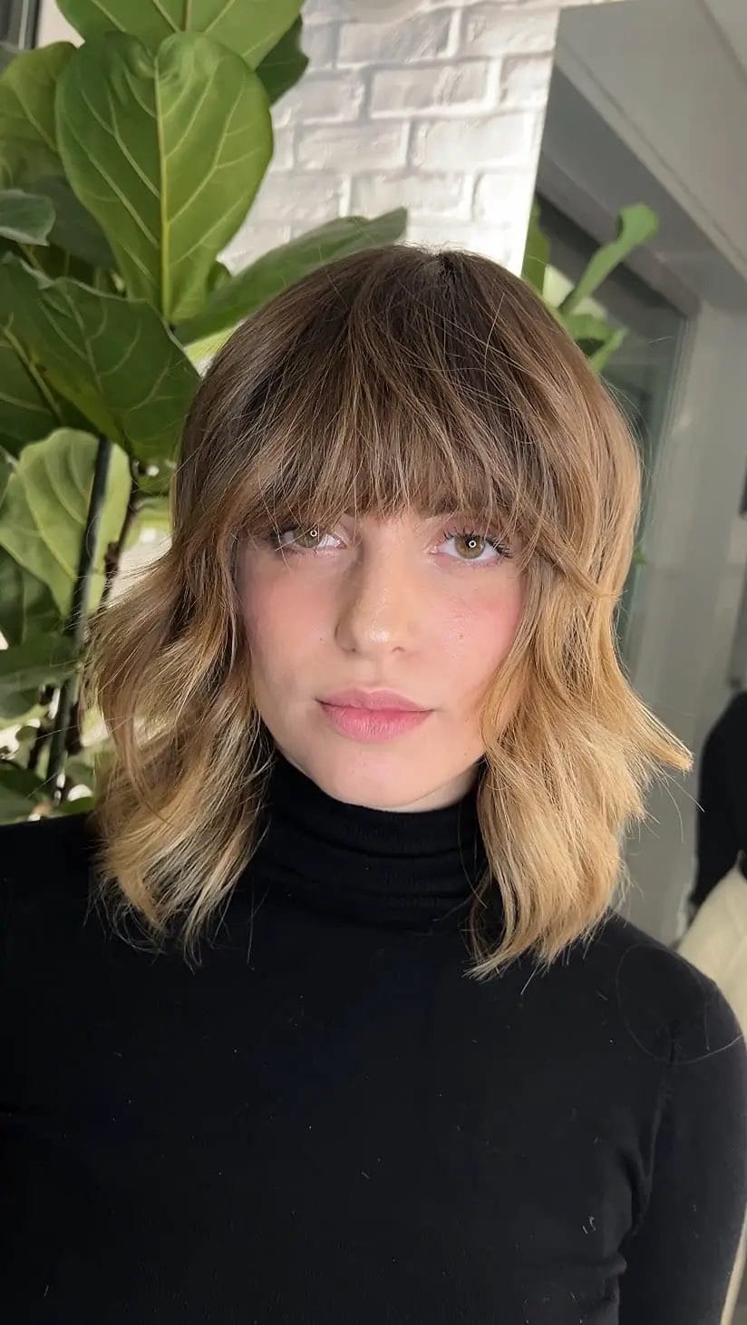 Warm blonde highlighted shaggy bob with soft fringe and layered bounce