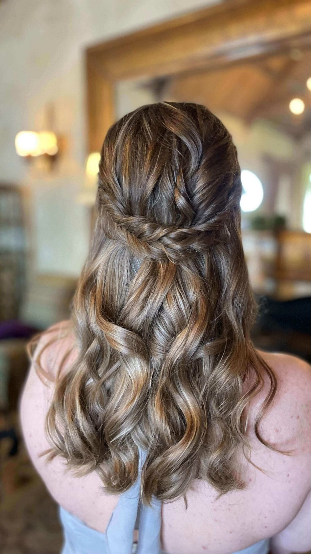 Classic curls enhanced by a cross-back braid in warm tones