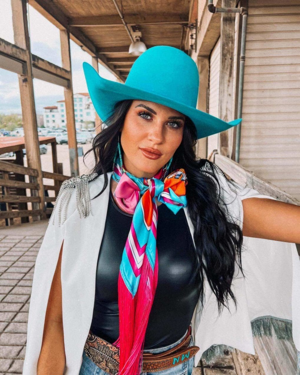 Long, wavy hair under a turquoise cowboy hat with a vibrant scarf