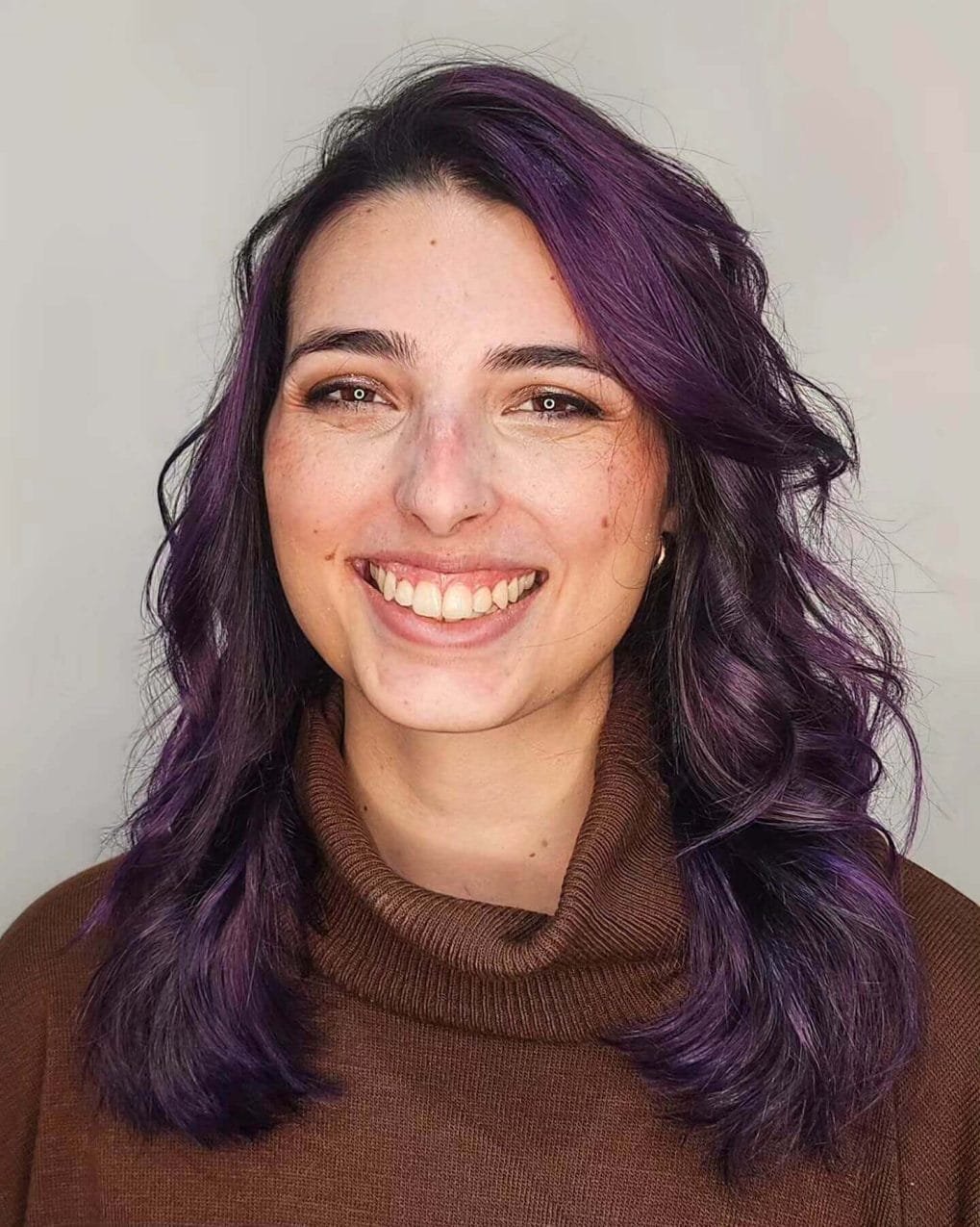 Wavy short butterfly haircut with vivid purple streaks.