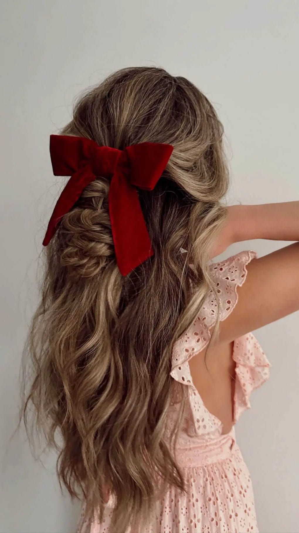 Tousled sun-kissed waves in a half-updo with a bold crimson bow for a birthday party.