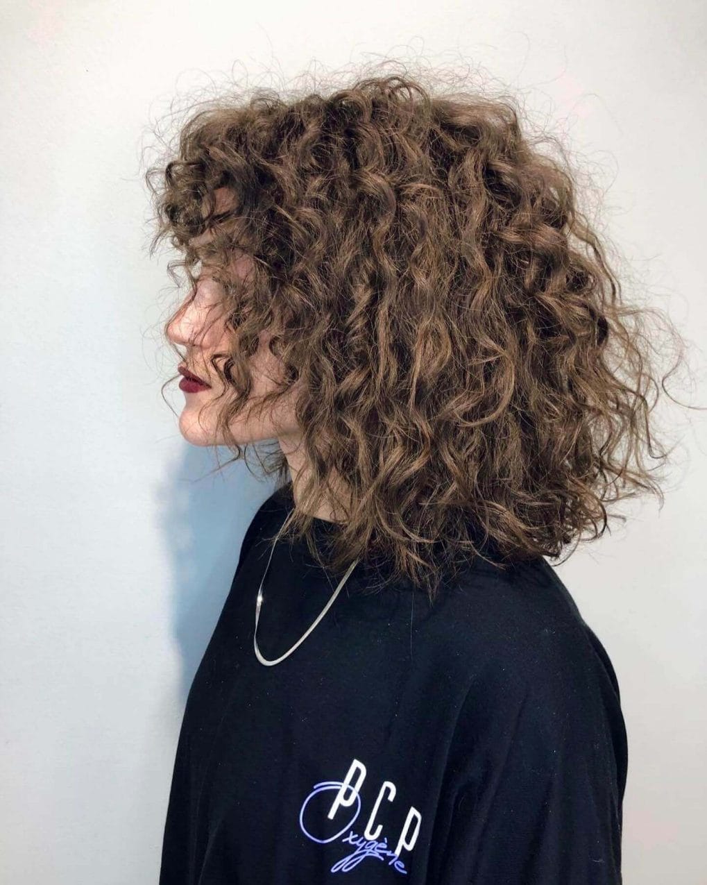 Wild and free-spirited mid-length curls with mocha tones.