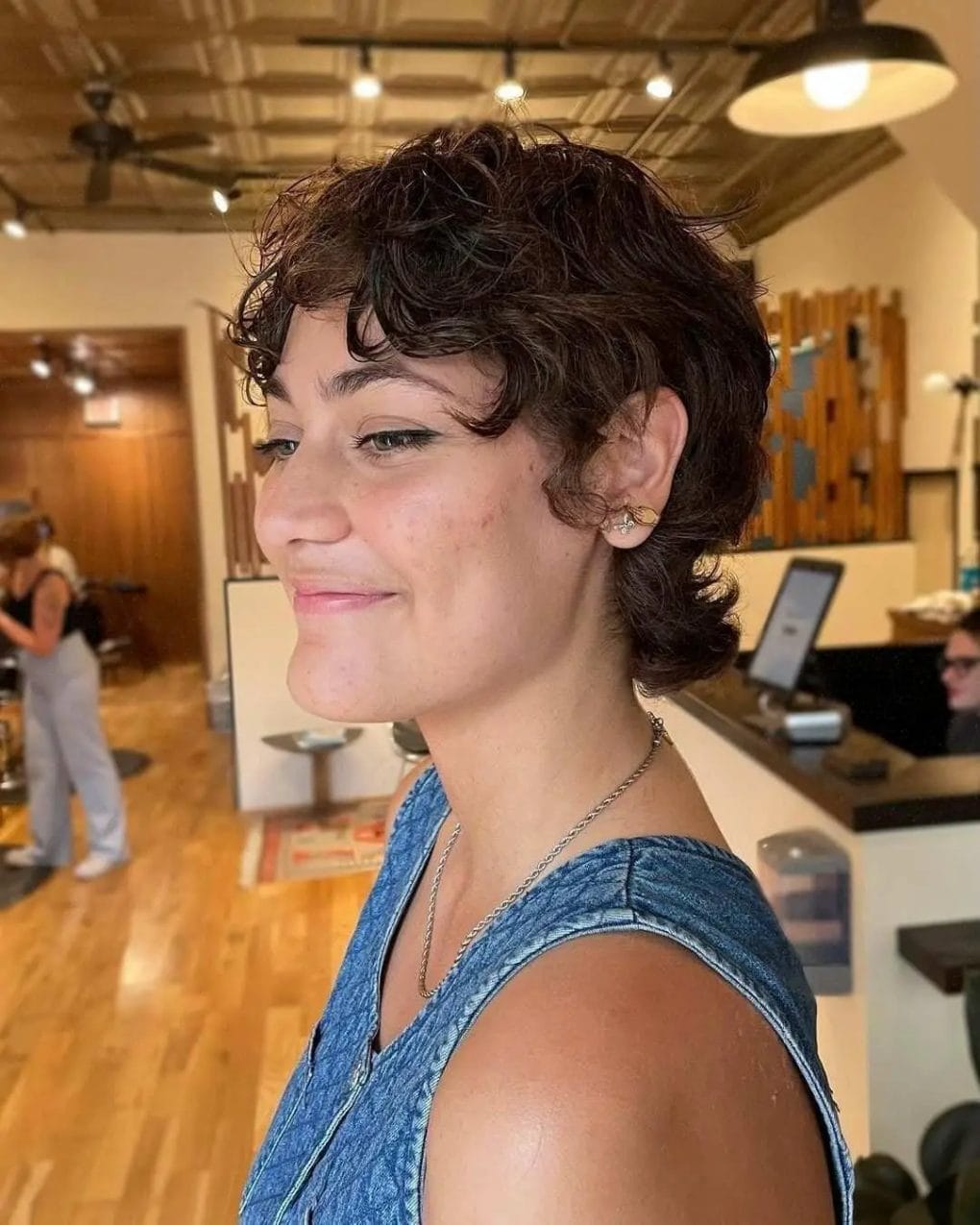 Curly textured pixie bob with shorter sides emphasizing voluminous curls on top